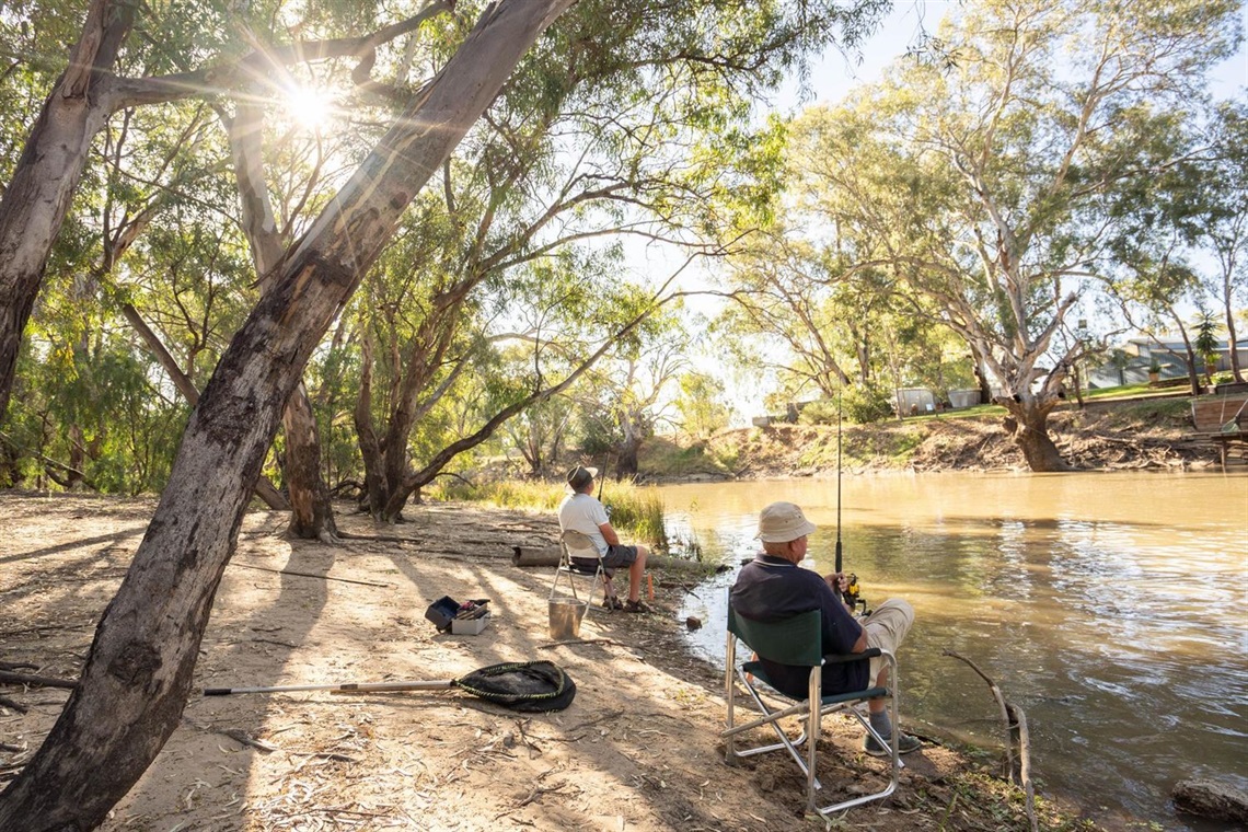 Two men sitting and fishing by Billabong Creek